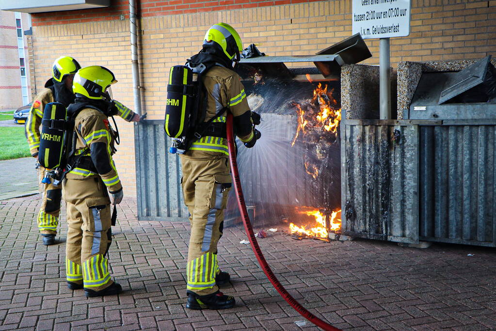 Containers onder flatgebouw in brand