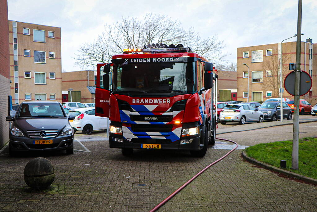 Containers onder flatgebouw in brand