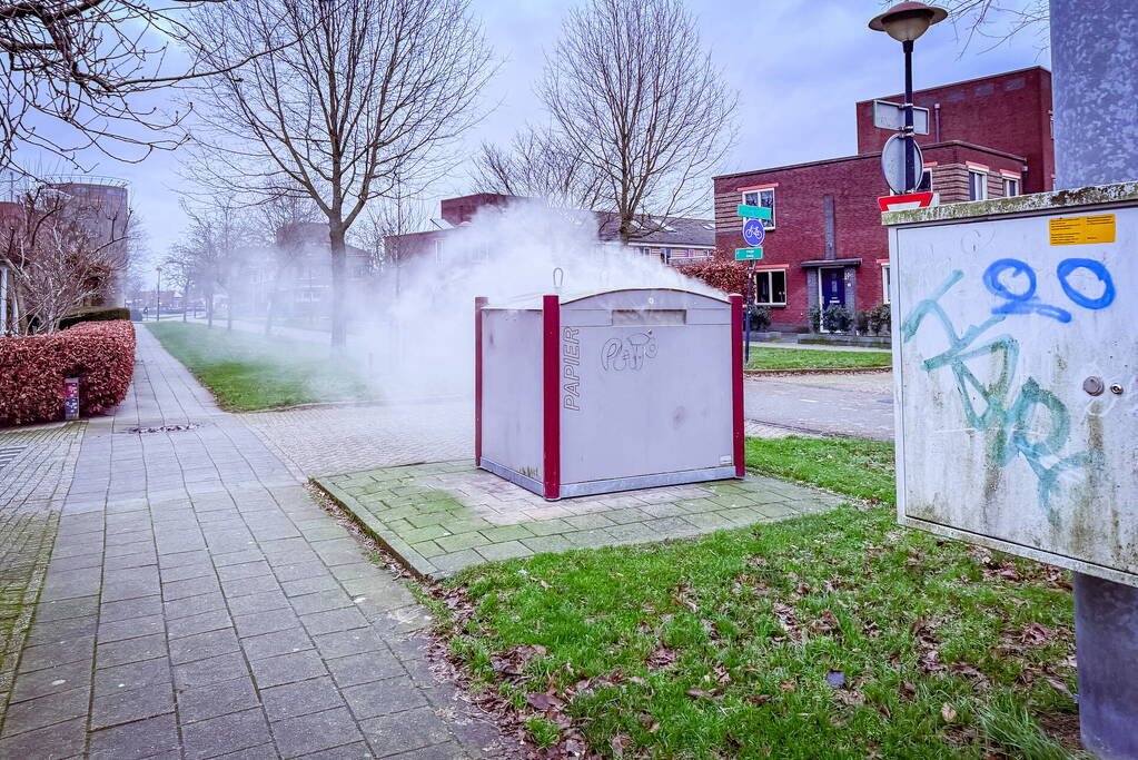 Brandweer blust brandende papiercontainer