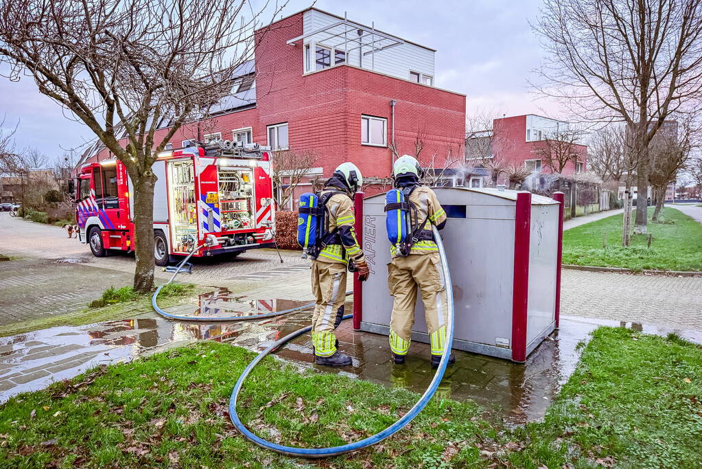 Brandweer blust brandende papiercontainer