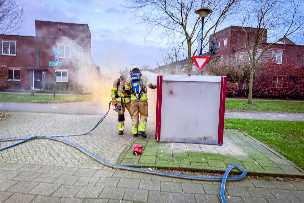 Brandweer blust brandende papiercontainer