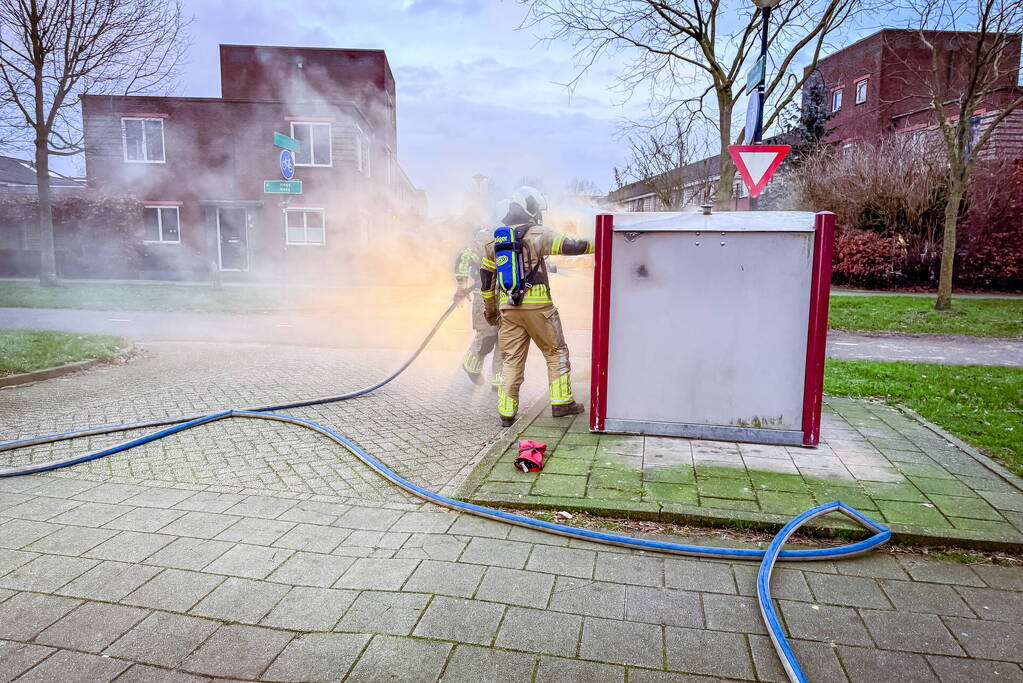 Brandweer blust brandende papiercontainer