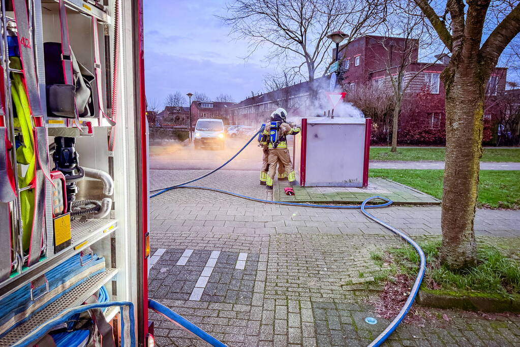 Brandweer blust brandende papiercontainer