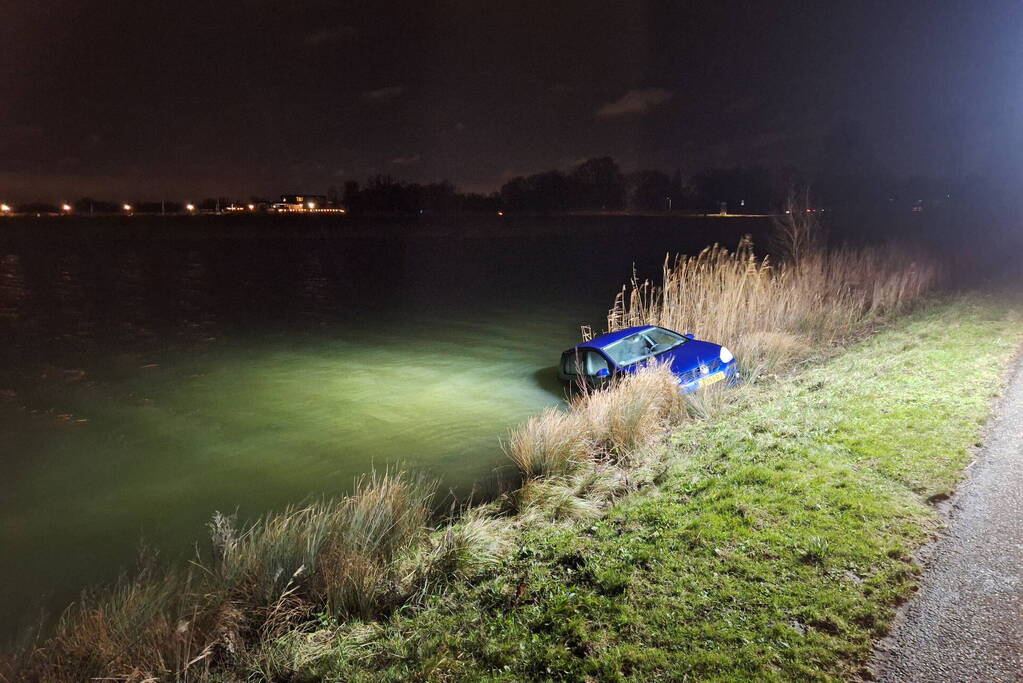 Auto met twee inzittenden rolt water in tijdens 