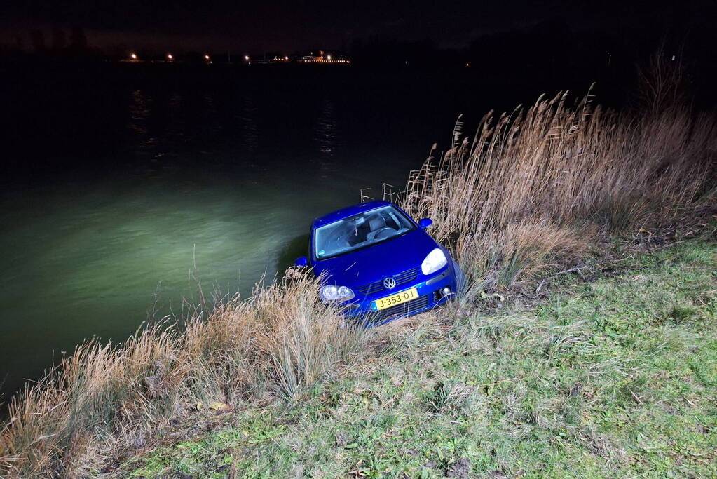 Auto met twee inzittenden rolt water in tijdens 