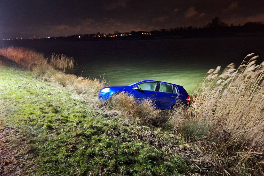 Auto met twee inzittenden rolt water in tijdens 