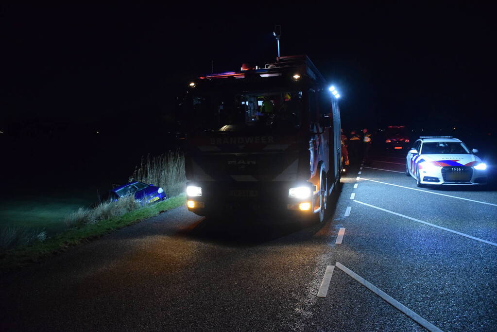 Auto met twee inzittenden rolt water in tijdens 