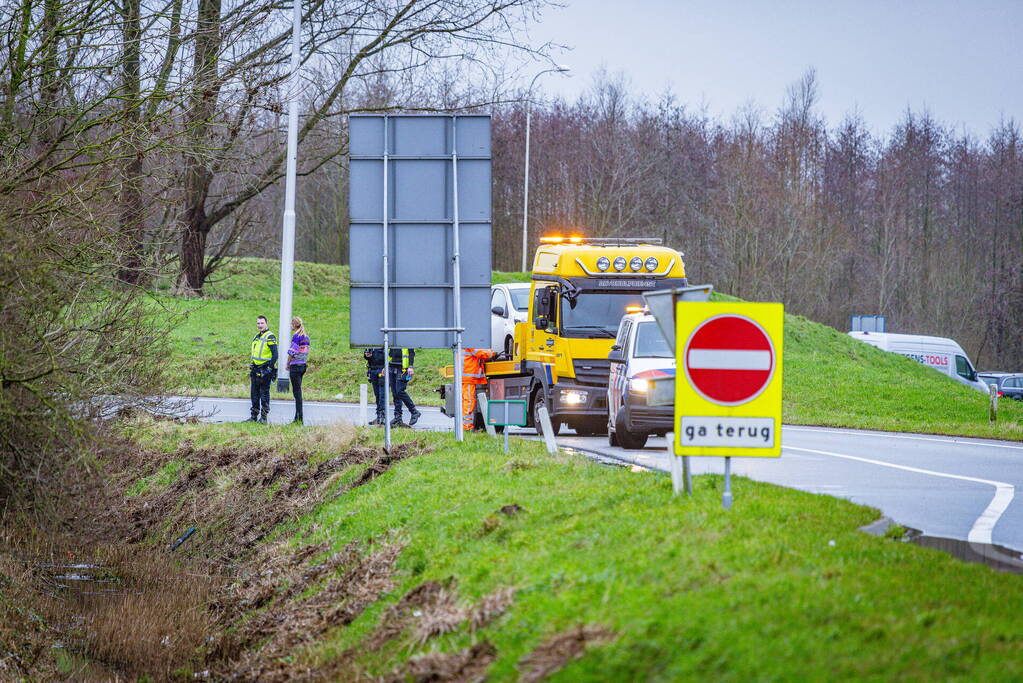 Auto raakt van de weg in bocht van afrit