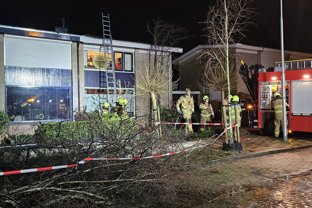 Grote boom waait om en belandt tegen woning