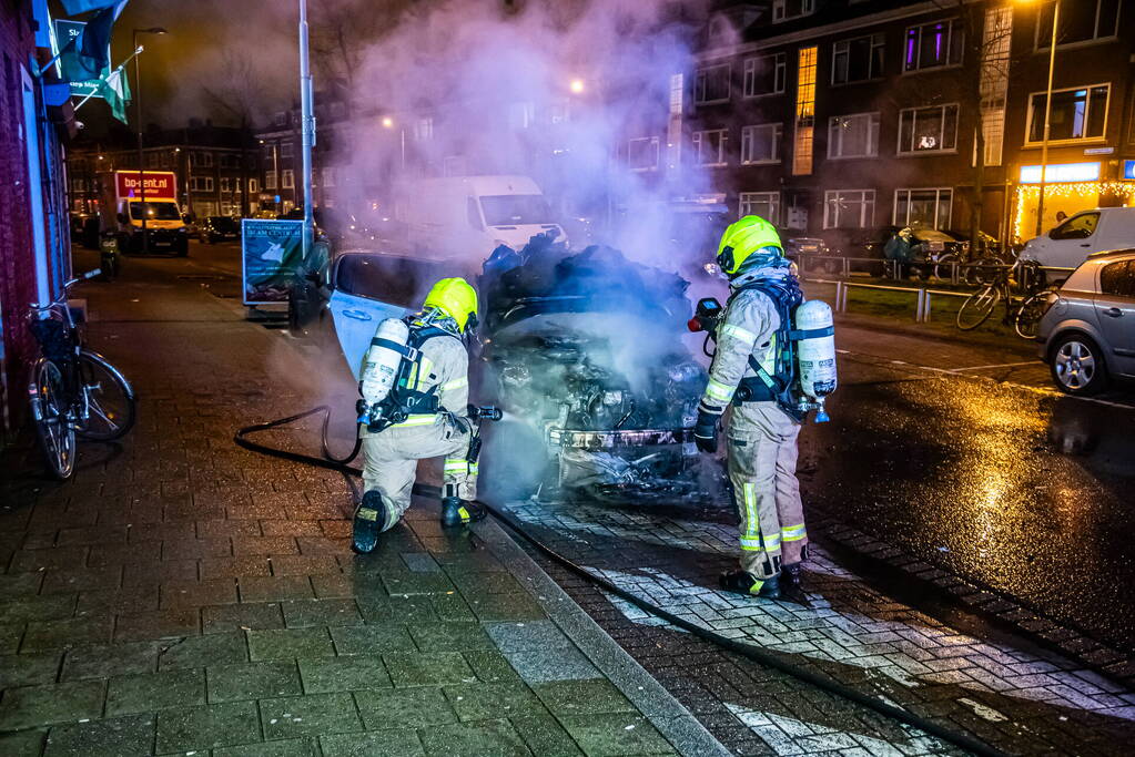 Brandweer blust in brand staande auto