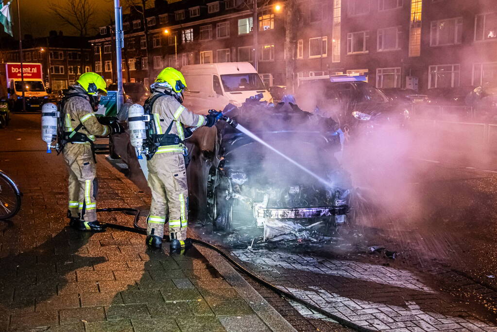 Brandweer blust in brand staande auto