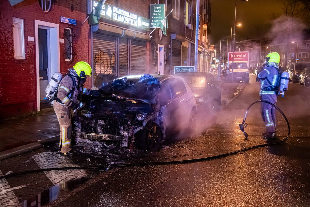 Brandweer blust in brand staande auto