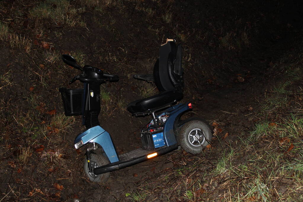 Persoon met scootmobiel in de sloot