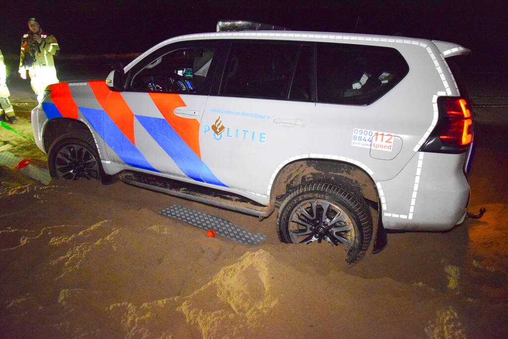 Politiejeep muurvast in los zand op strand