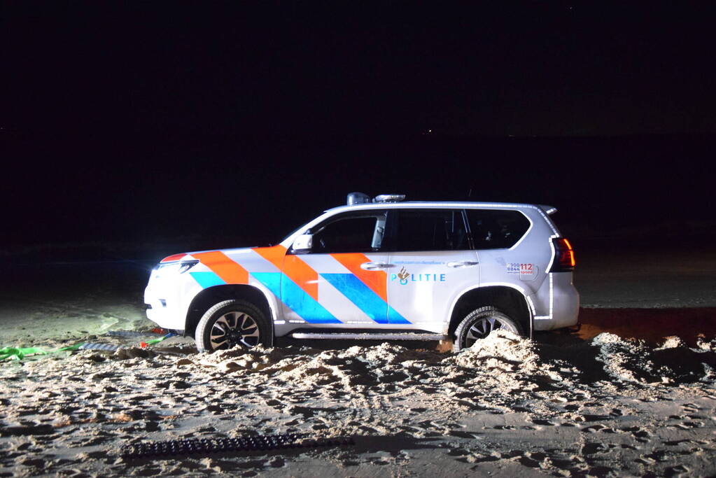 Politiejeep muurvast in los zand op strand