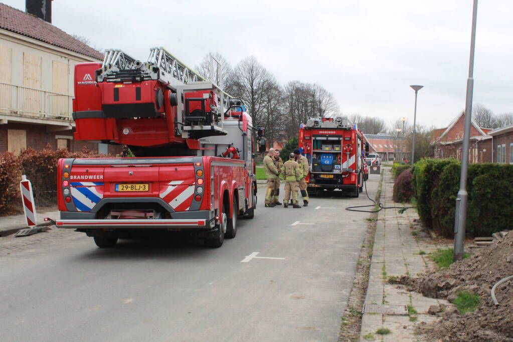 Brandweer blust brandend afval achter sloopwoningen