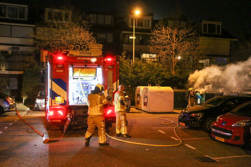 Brandweer blust brandende papiercontainer