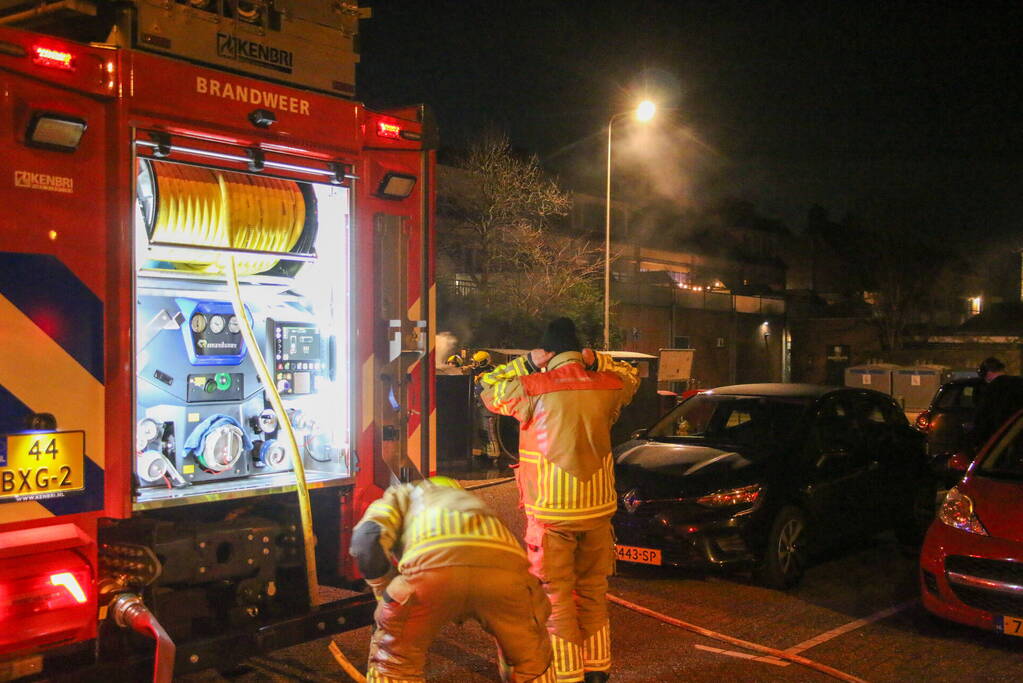 Brandweer blust brandende papiercontainer