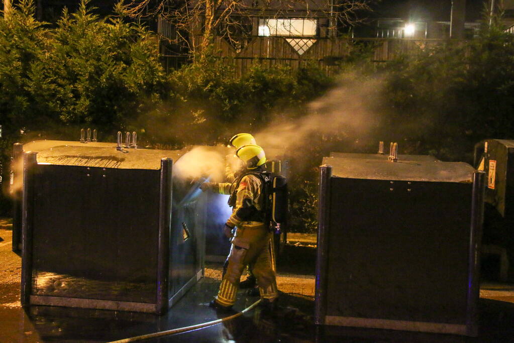 Brandweer blust brandende papiercontainer