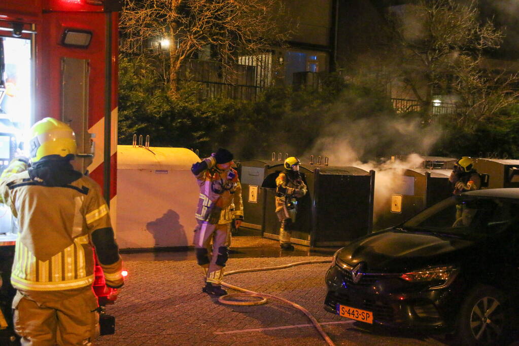 Brandweer blust brandende papiercontainer