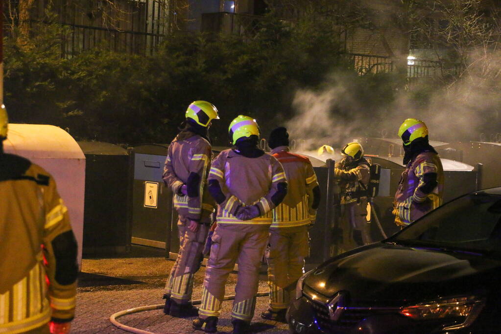 Brandweer blust brandende papiercontainer