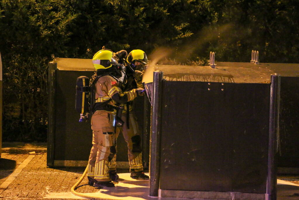 Brandweer blust brandende papiercontainer