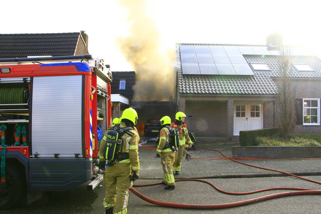 Personenauto vat vlam onder carport