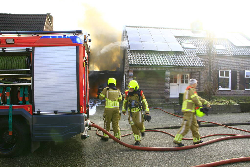 Personenauto vat vlam onder carport