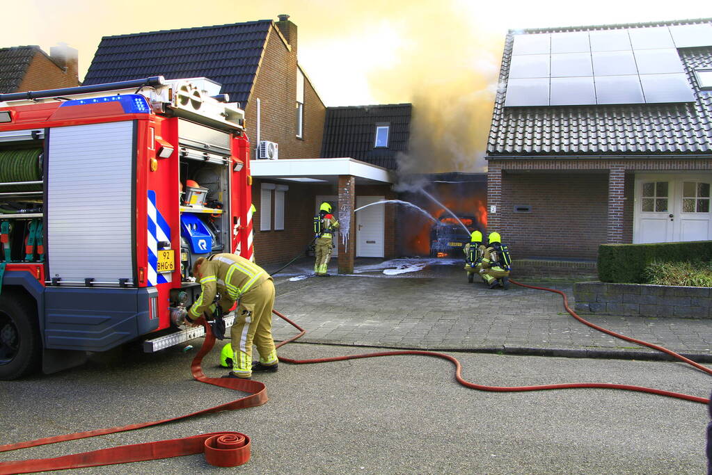 Personenauto vat vlam onder carport