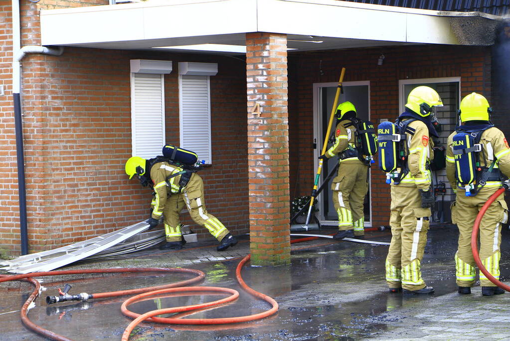 Personenauto vat vlam onder carport