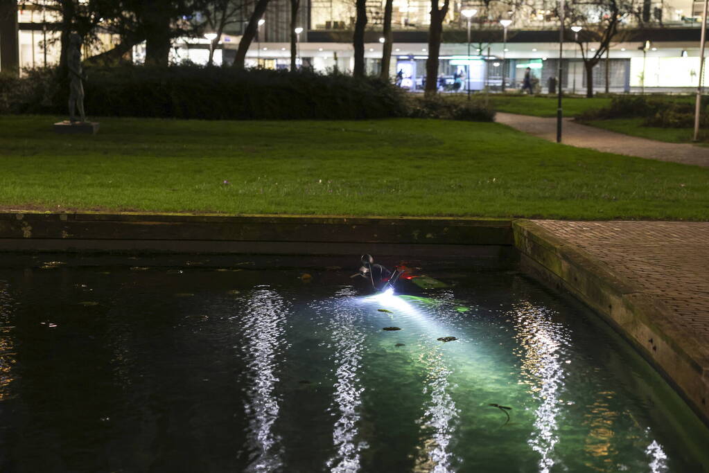 Personen dumpen scooter in vijver met karpers