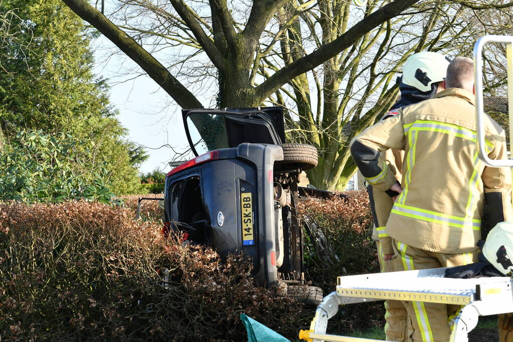 Auto raakt van de weg en belandt op zijkant in voortuin