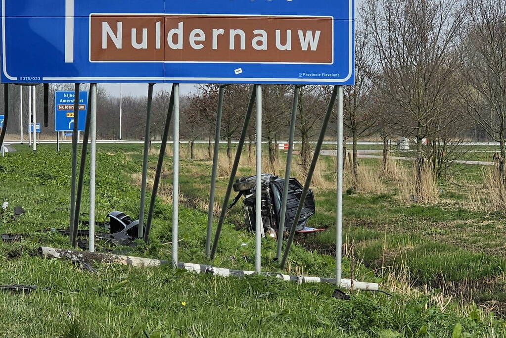 Auto ramt verkeerslicht en belandt op zijn zij in een greppel