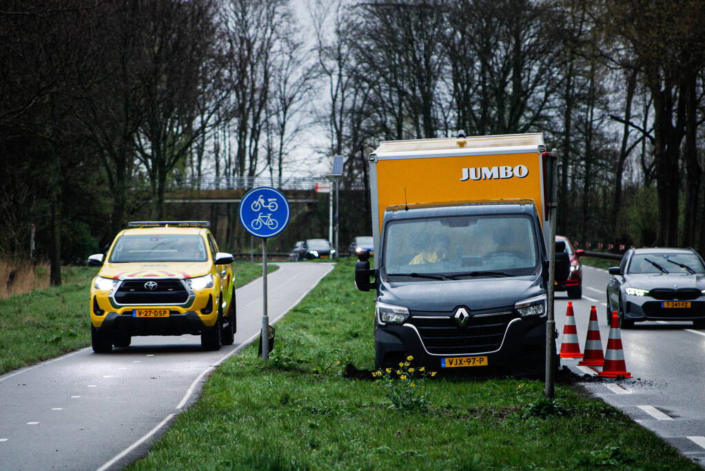 Jumbo bezorger raakt met bakwagen van weg en komt vast te zitten