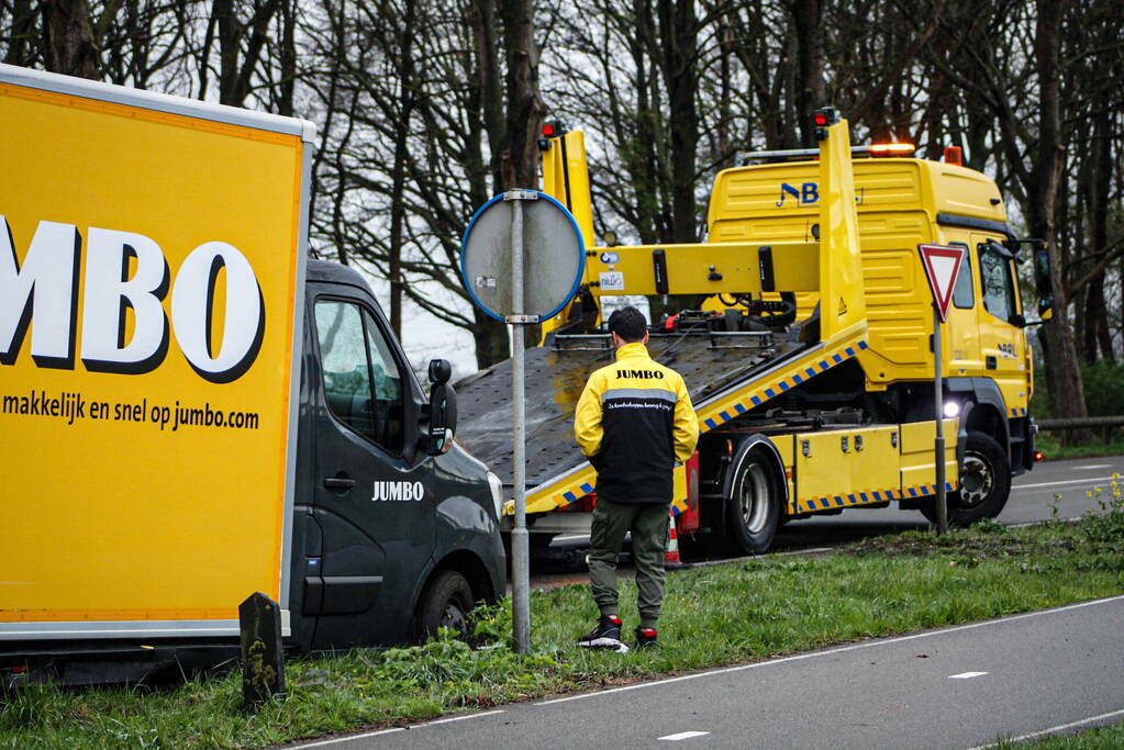 Jumbo bezorger raakt met bakwagen van weg en komt vast te zitten