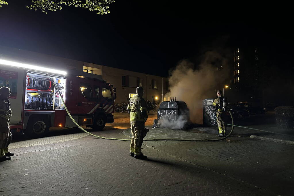 Brandweer blust brandend afval naast container