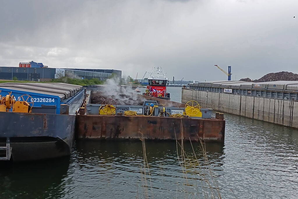 Brandweerboot inspecteert dampende duwbak