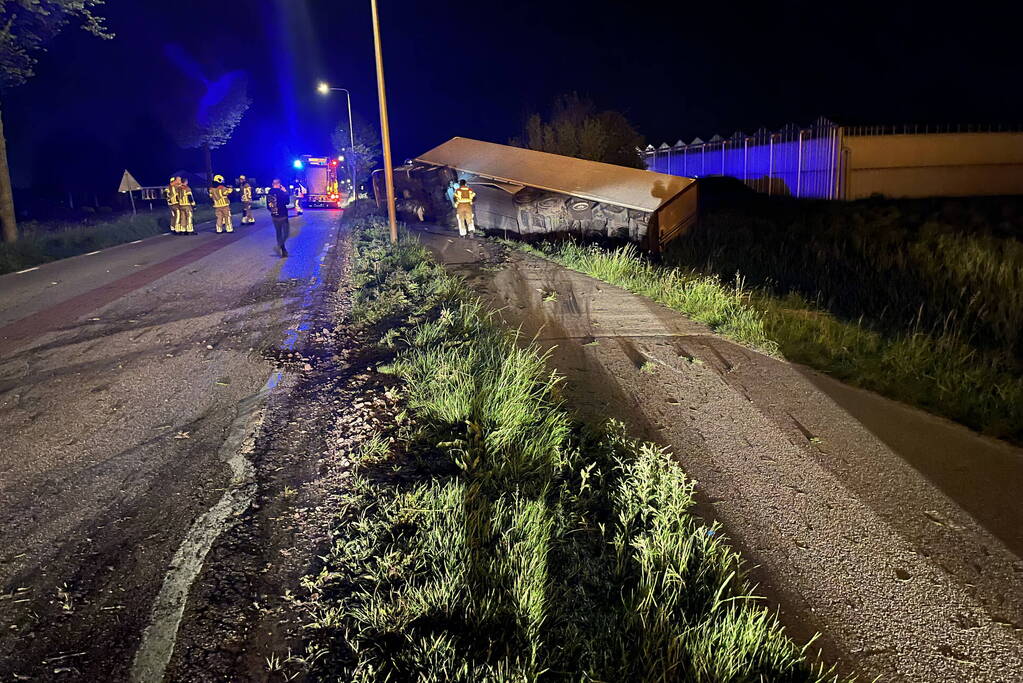 Vrachtwagen ramt boom en belandt op zijkant in sloot