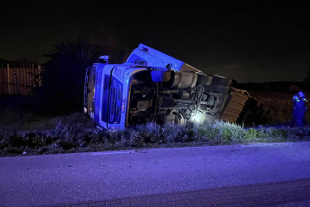 Vrachtwagen ramt boom en belandt op zijkant in sloot