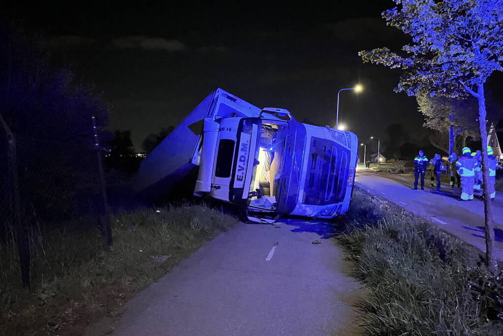 Vrachtwagen ramt boom en belandt op zijkant in sloot