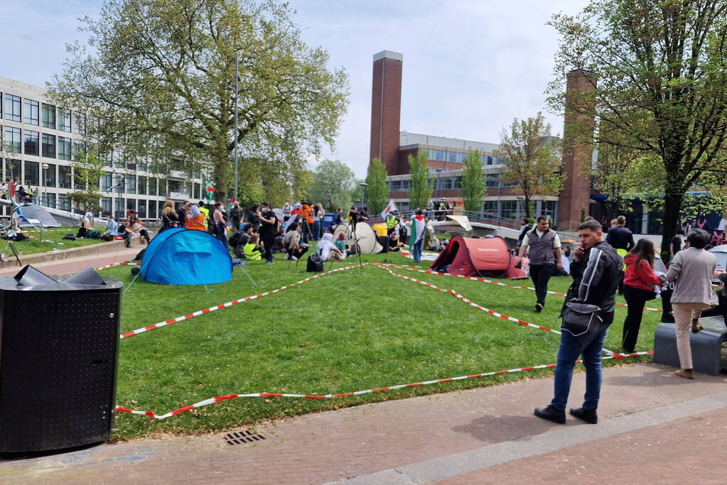 Studenten in tenten op grasveld bij UvA