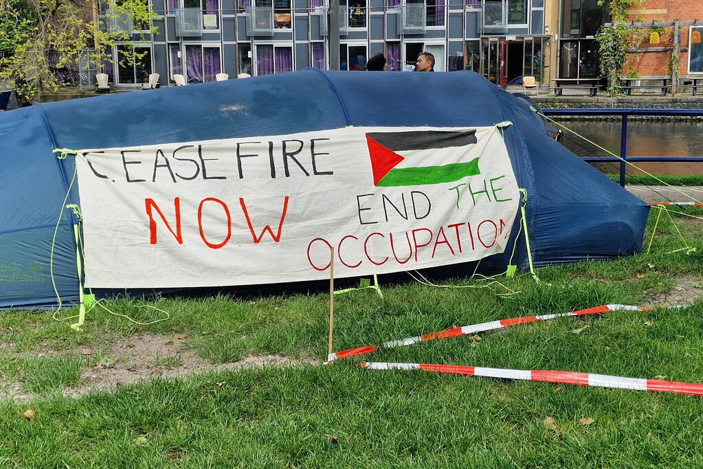 Studenten in tenten op grasveld bij UvA