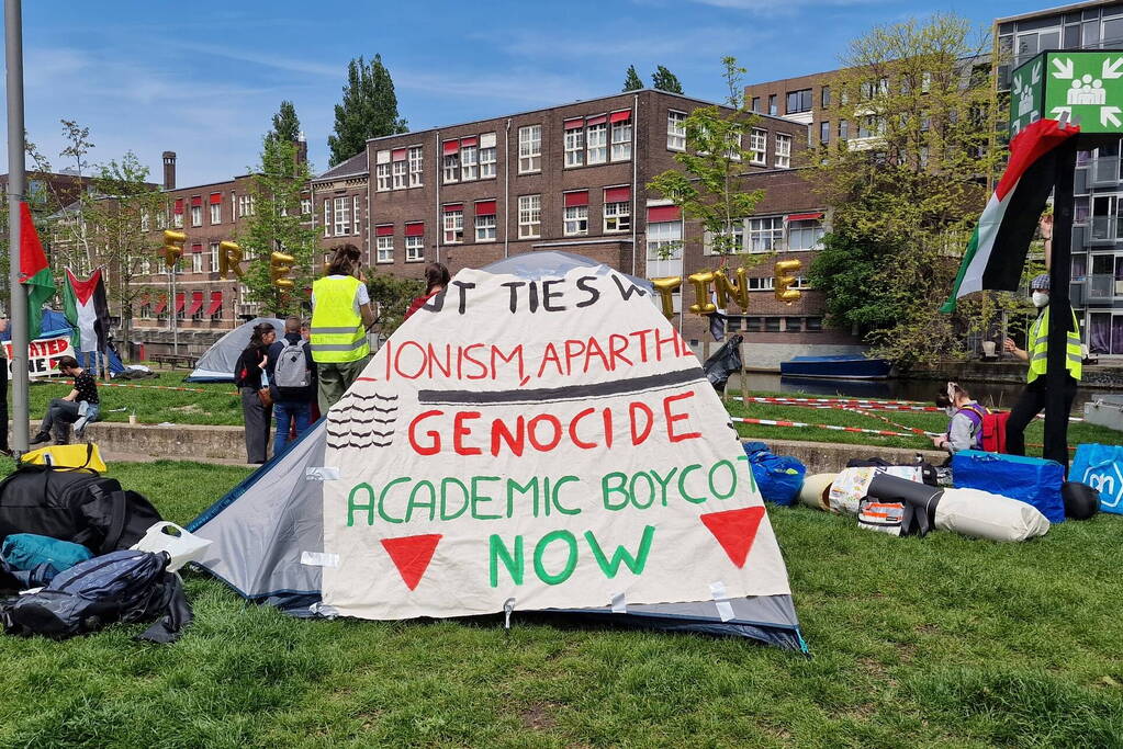 Studenten in tenten op grasveld bij UvA