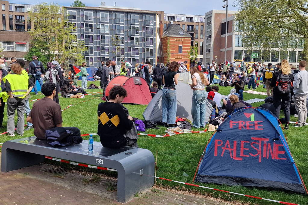 Studenten in tenten op grasveld bij UvA