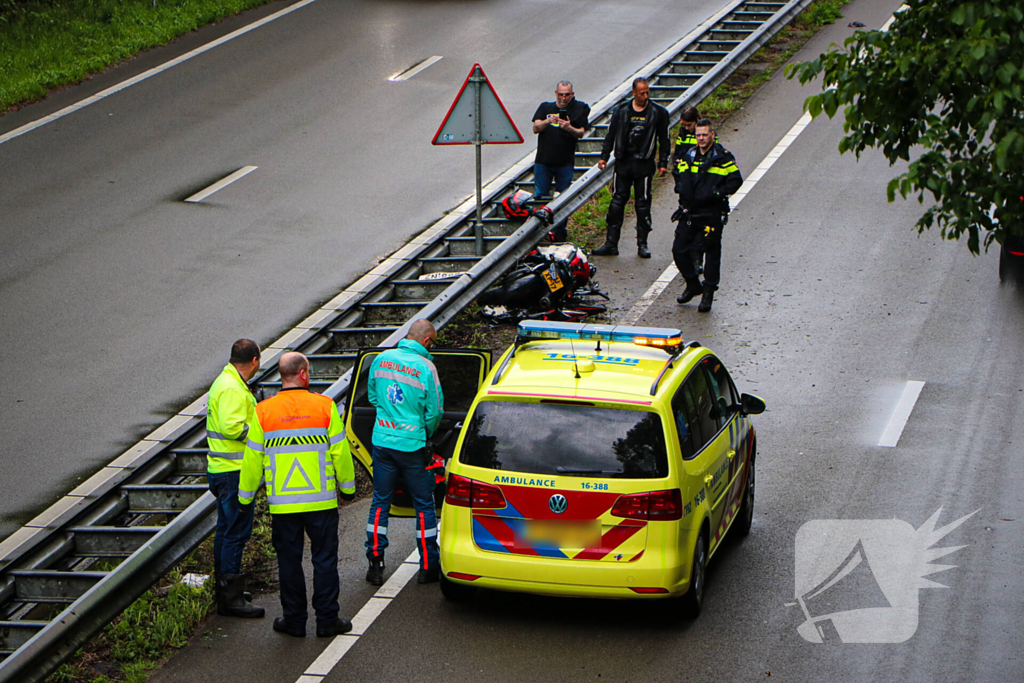 Motorrijder hard onderuit door water onder viaduct