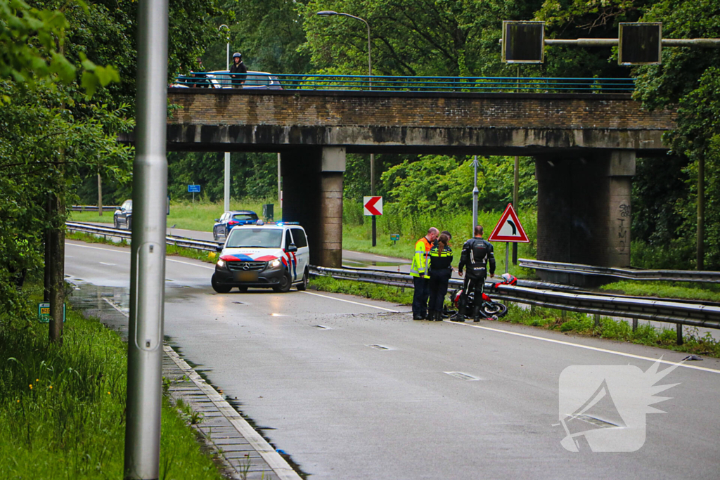 Motorrijder hard onderuit door water onder viaduct