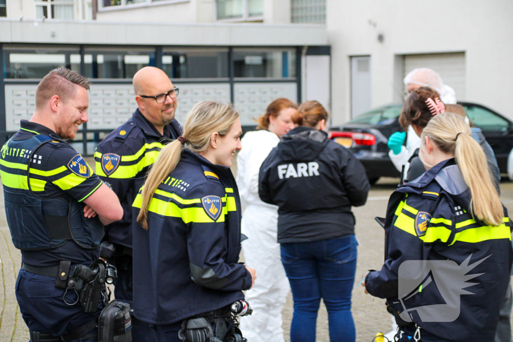 Forensisch onderzoek op parkeerplaats naast flatgebouw