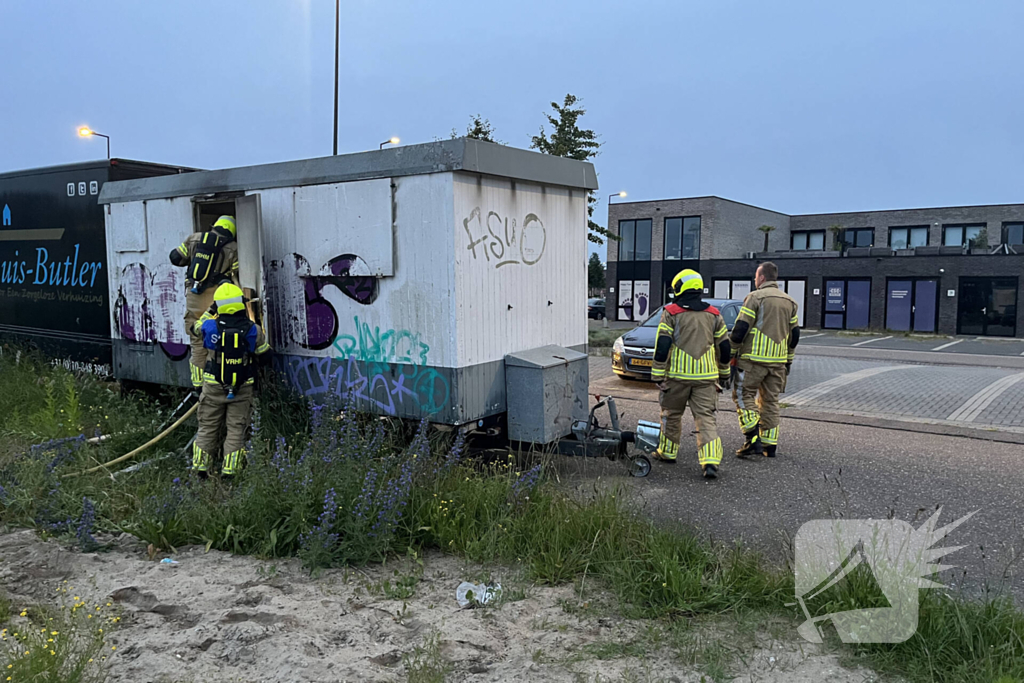 Brandweer blust in brand gestoken bouwkeet vol rommel