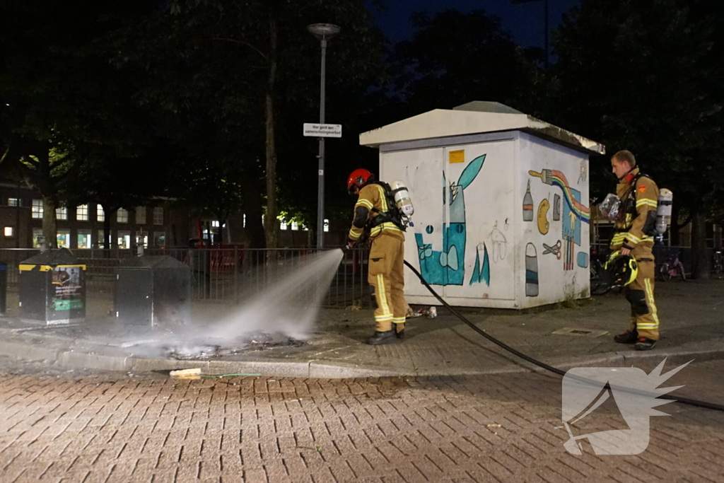 Brandweer blust brand naast afvalcontainer