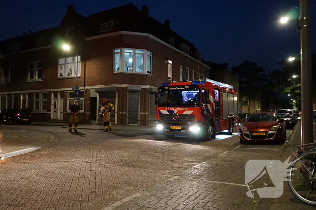 Brandweer blust brand naast afvalcontainer